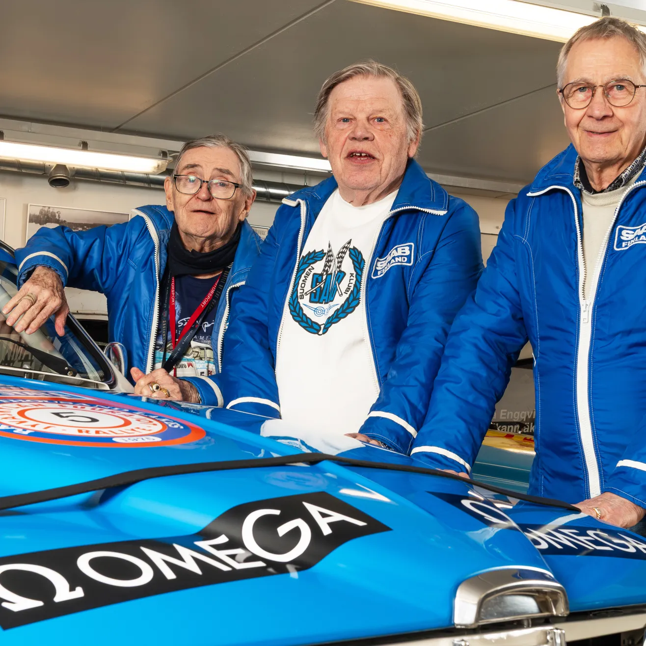 50 vuotta aikaa kuvien välissä. Saabin rallitallin kuljettajat Simo Lampinen, Jari Vilkas ja Tapio Rainio 1970-luvulla ja sama kolmikko peilikuvana 2026.